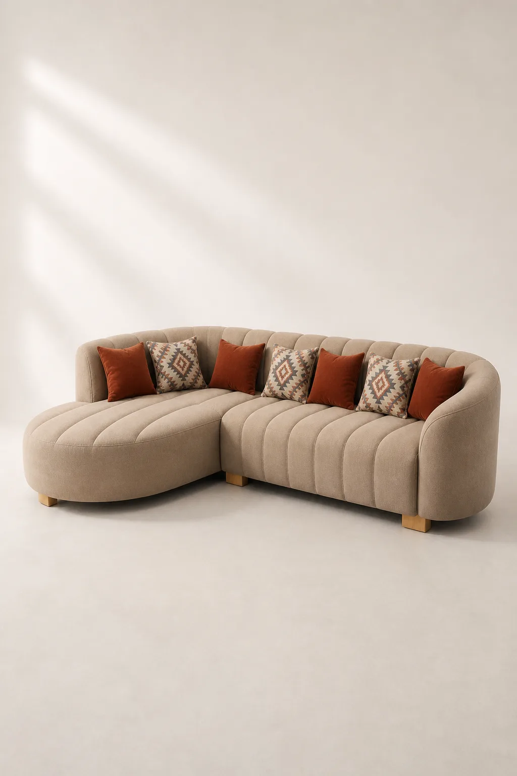 Taupe channel-tufted curved L-shaped sofa with rust and kilim-pattern cushions.